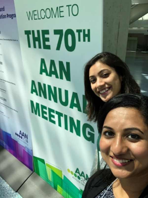 Two students pose in front of a sign denoting the 70th AAN Annual Meeting.